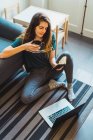 Junge Frau sitzt zu Hause am Laptop mit Notizbuch in der Hand am Boden — Stockfoto