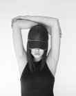 Досить стильна жінка в шапці позує з піднятими схрещеними руками в студії — стокове фото