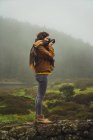 Woman taking photo on background of misty woods — Stock Photo