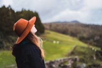 Side view young woman in hat posing at countryside — Stock Photo
