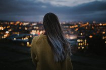 Вид ззаду жінка захоплюється освітленим міським пейзажем — стокове фото