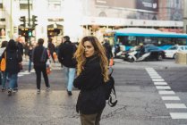 Красива жінка з рюкзаком, озираючись назад на міську дорогу . — стокове фото
