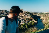 Турист оглядывается через плечо на город в горах — стоковое фото