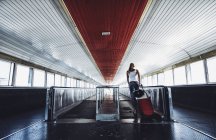 Rückansicht einer Frau mit Koffer, die auf Reisenden am Bahnhof tritt. — Stockfoto