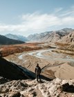 Вид сзади туриста, стоящего на скале в долине реки — стоковое фото