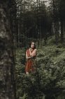 Brunette girl in dress standing in spooky woods — Stock Photo