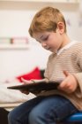 Blonder Junge spielt zu Hause mit Tablet — Stockfoto