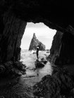 Silhouette of woman standing at rock at coast cave — Stock Photo