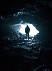 Silhouette di persona irriconoscibile in piedi all'ingresso della grotta . — Foto stock