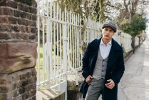 Stylish man in vintage clothes posing near gate — Stock Photo