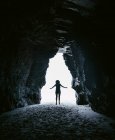 Путешественник позирует у входа в каменную пещеру — стоковое фото