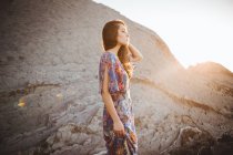Нежная брюнетка в летнем платье позирует на скалистой местности — стоковое фото