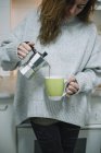 Woman pouring coffee in cup on kitchen — Stock Photo