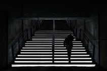 Back view of woman walking up on illuminated stairs. — Stock Photo