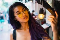 Junge Frau mit gelber Brille schaut auf Glühbirne — Stockfoto