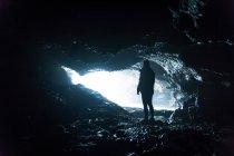 Silhueta em pé pela entrada da caverna — Fotografia de Stock
