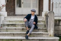 Mann in Vintage-Kleidung sitzt auf Veranda und schaut zur Seite — Stockfoto