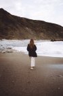Вид ззаду жінки, що йде на березі океану — стокове фото