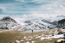 Vue arrière du touriste debout sur le terrain au lac dans les montagnes enneigées . — Photo de stock