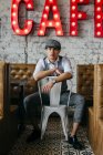 Homem de roupas vintage posando na cadeira no café — Fotografia de Stock