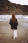 Vue arrière de la femme marchant le long du rivage de l'océan — Photo de stock