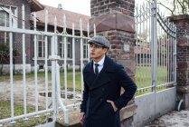 Man in vintage clothes walking along gate at street scene — Stock Photo