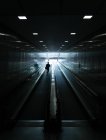 Silhouette of unrecognizable man riding on moving walkway. — Stock Photo