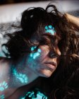 Frau mit fluoreszierenden Pfotenabdrücken im Gesicht — Stockfoto