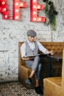Man in vintage clothes sitting at cafe table and reading newspaper — Stock Photo