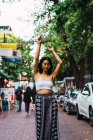 Jolie jeune femme posant les bras levés sur la scène de rue — Photo de stock