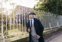 Man in vintage clothes walking near gate and looking over shoulder — Stock Photo