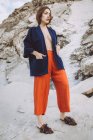 Брюнетка в модном пиджаке на обнаженном теле уверенно позирует на камне — стоковое фото