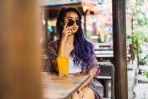 Молода жінка позує з сонцезахисними окулярами за столом кафе — стокове фото