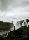 Турист стоїть над каскадом водоспаду на фоні — стокове фото