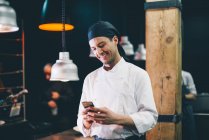 Веселый шеф-повар со смартфоном на кухне — стоковое фото