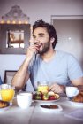 Homem feliz tomando café da manhã na cozinha — Fotografia de Stock