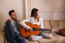 Frau spielt zu Hause Gitarre für Freund — Stockfoto