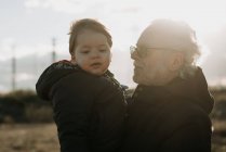Homme âgé portant petit-fils dans les bras — Photo de stock