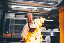 Fire flame over cook making flambe in restaurant — Stock Photo