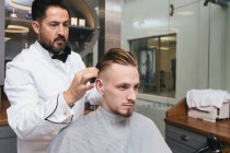 Barber styling hair of male customer — Stock Photo