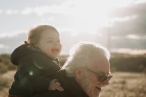 Uomo anziano che porta il nipote sul retro — Foto stock