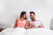 Couple gai avec tablette au lit — Photo de stock