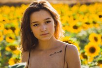 Красива молода жінка позує в соняшниках — стокове фото