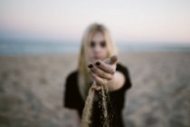 Weibliche Hand schüttet Sand am Meer — Stockfoto