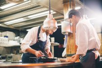 Uomini che lavorano in cucina e fanno piatti sul bancone — Foto stock
