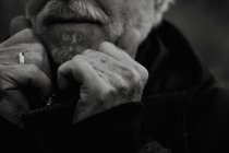 Black and white crop shot of elderly elegant man holding collar of black jacket. — Stock Photo