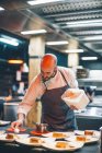 Chef adicionando molho em pratos na cozinha do restaurante — Fotografia de Stock