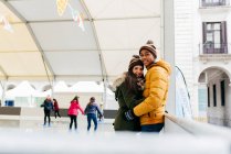 Fröhliches Paar umarmte sich auf Eisbahn — Stockfoto