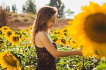 Side view of smiling woman in sunflowers — Stock Photo