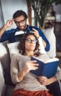 Giovane coppia lettura libri sul divano a casa — Foto stock